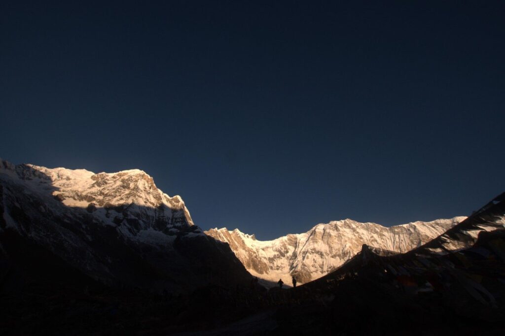 Sunrise glow on Himalayan peaks with prayer flags at Annapurna Base Camp