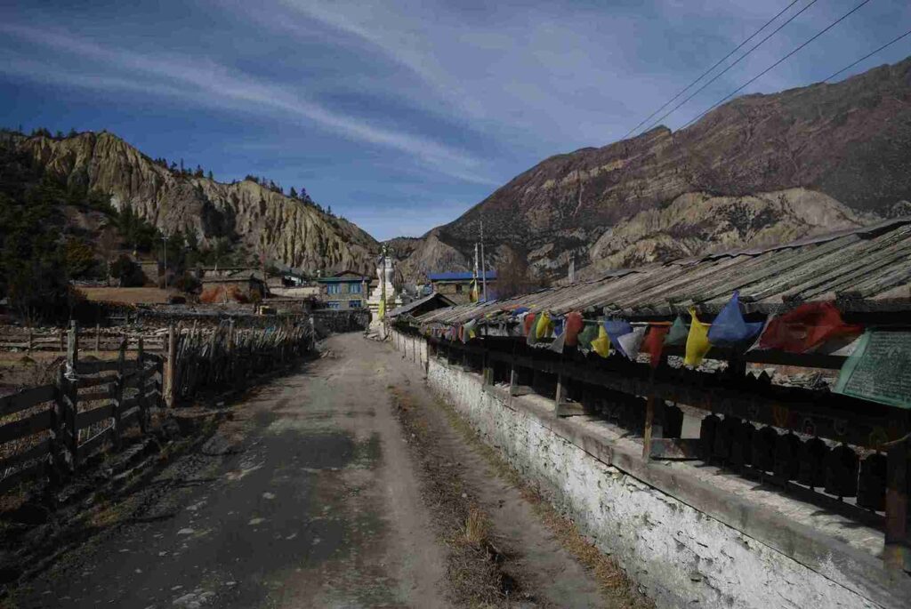 Village road lined with a mani wall and prayer flags on the Annapurna Circuit Trek