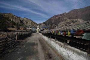 Village road lined with a mani wall and prayer flags on the Annapurna Circuit Trek