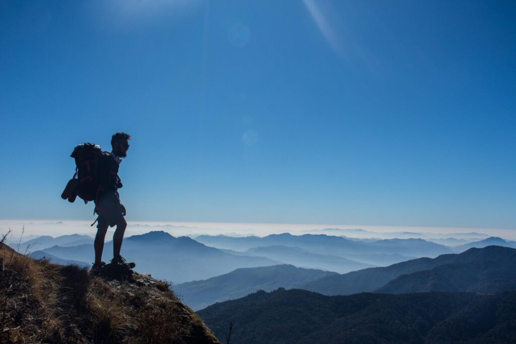 Trekker standing on a ridge overlooking layered Himalayan mountains
