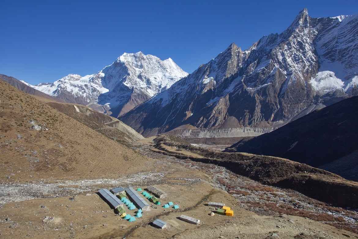 Trekking camp tents in valley beneath Himalayan peaks