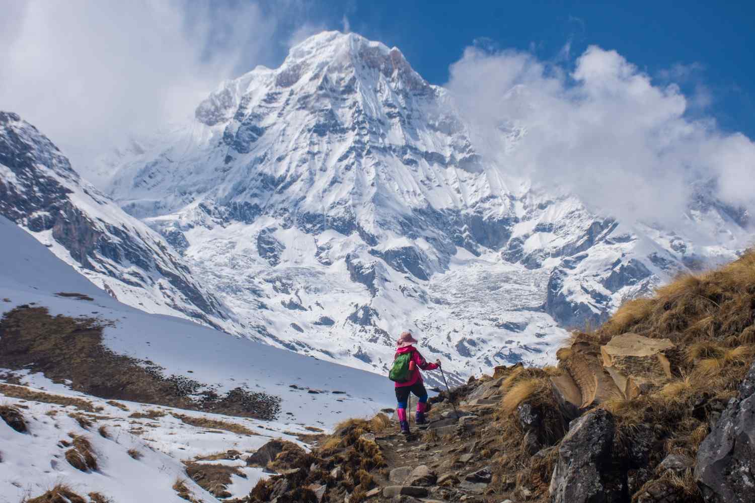 Woman trekker walking a snowy trail toward Annapurna peak