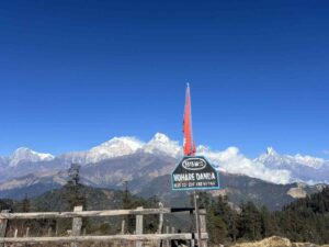 Mohare Danda viewpoint sign at 3313m with Nepali flag and Annapurna mountain range in the background