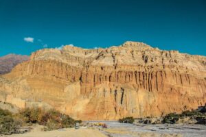 Layered sandstone canyon cliffs above a dry riverbed in mustang