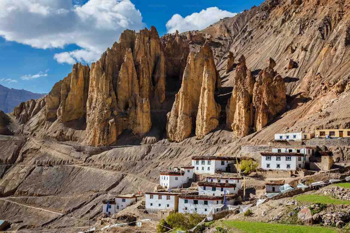 Himalayan village beneath eroded golden rock spires
