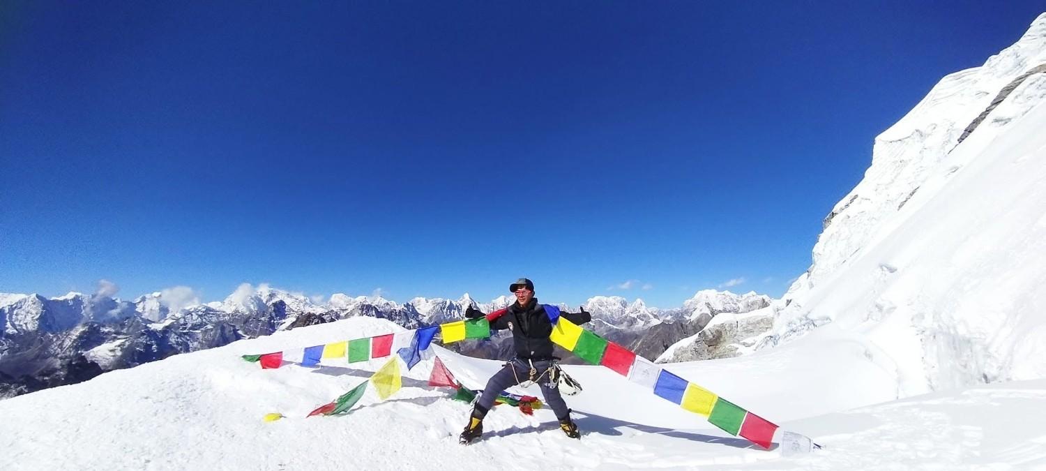 Climber celebrating on Island Peak summit with prayer flags